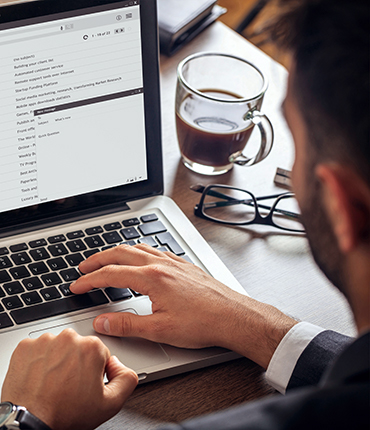 a man reading and responding to an email on his laptop